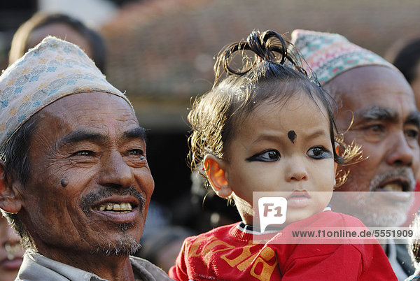 Männer mit traditioneller Kopfbedeckung und Kind beobachten Prozession  Taumadhi-Platz  Bhaktapur  Kathmandu-Tal  Nepal  Asien