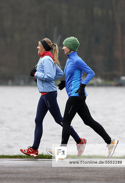 Two young women jogging in winter  wearing wind and waterproof performance apparel