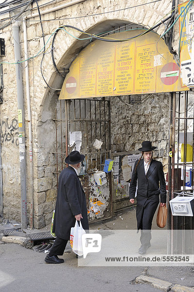 Sign prohibiting the entry of non-Orthodox Jews in a residential housing estate  with two Orthodox Jews passing through the gateway  in the district of Me'a She'arim or Mea Shearim  Jerusalem  Israel  Middle East