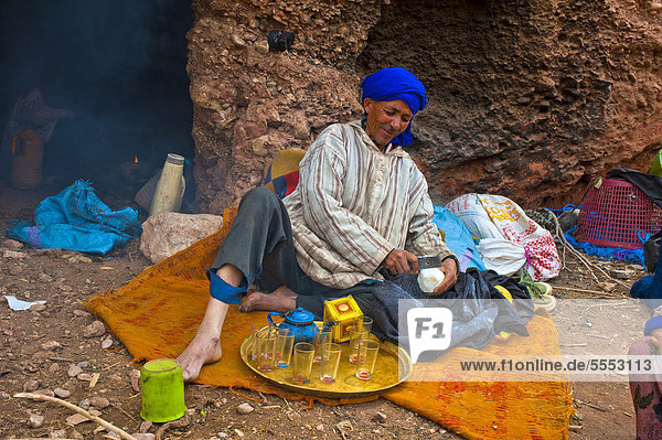 Berber man wearing a blue turban using a metal blade to shave off pieces of sugar for his tea  nomadic cave dweller  Dades Valley  southern Morocco  Morocco  Africa