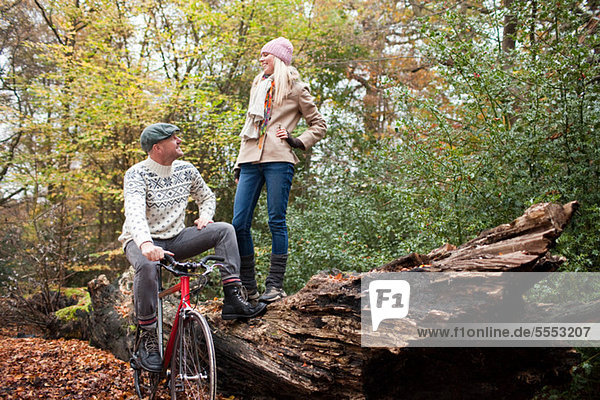 Man with bike and woman standing on log