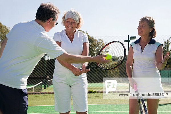 Senioren und Erwachsene üben auf Tennisplätzen