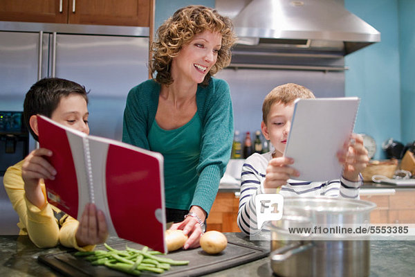 Mittlere erwachsene Frau beim Kochen in der Küche mit Söhnen