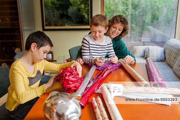 Woman and sons wrapping gifts at table