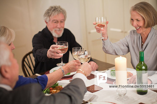 Leitende Freunde erhöhen Glasses at Dinner-party
