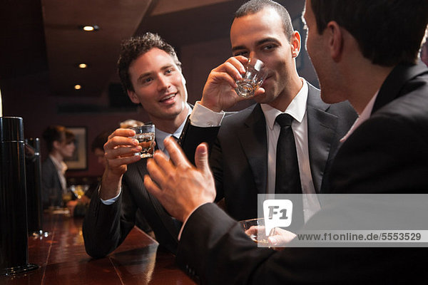 Drei Geschäftsleute  die in einer Bar trinken.