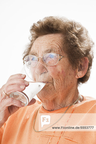 Alte Frau mit Brille trinkt ein Glas Milch