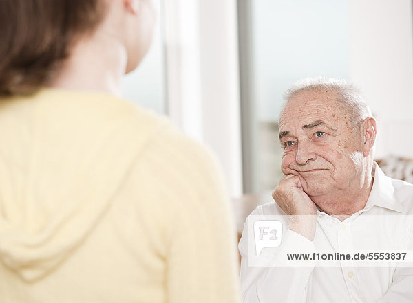 Serious senior man looking at young woman