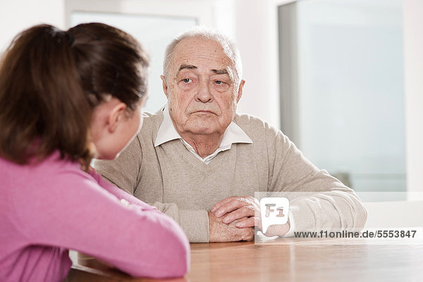 Young woman and senior man sitting at table