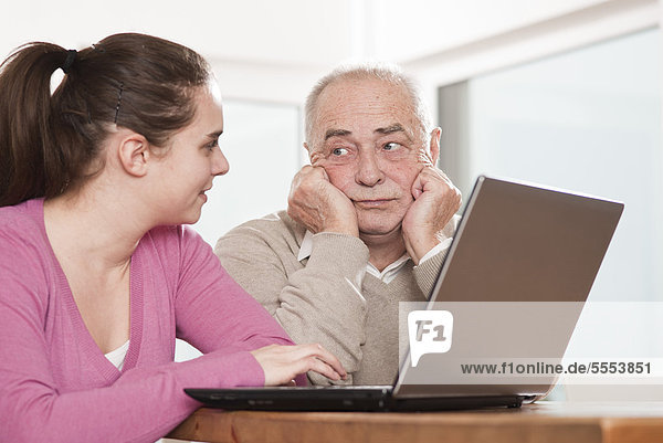 Young woman and frustrated senior man using laptop