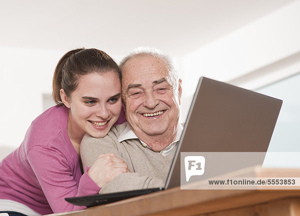 Happy young woman and senior man using laptop