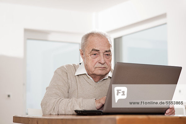 Senior man using laptop at table