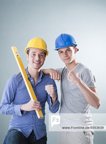 Two young men wearing hard hats showing their muscles  portrait