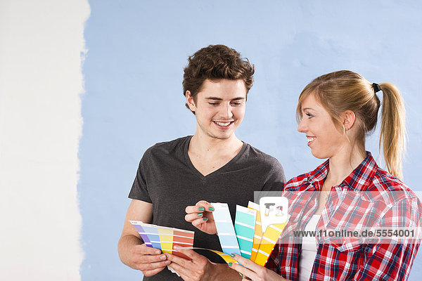 Junges Paar betrachtet verschiedene Wandfarben