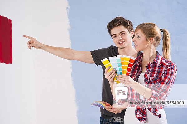 Junges Paar betrachtet verschiedene Wandfarben