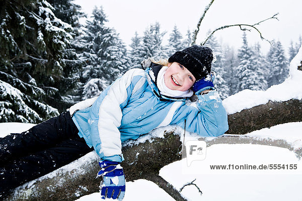 Girl on a tree trunk in the snow