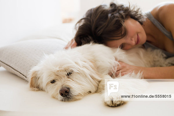 Frau entspannt mit Hund im Bett