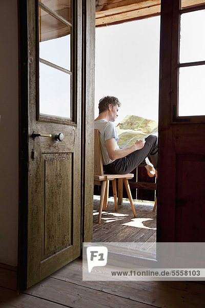 Mann liest auf der Veranda