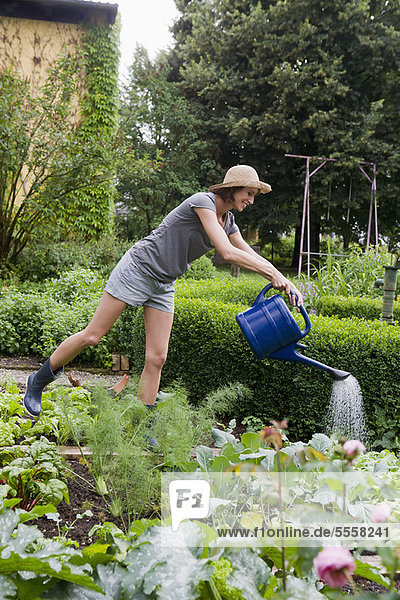 Frau bewässert Pflanzen im Hinterhof