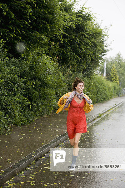 Lächelnde Frau  die im Regen rennt