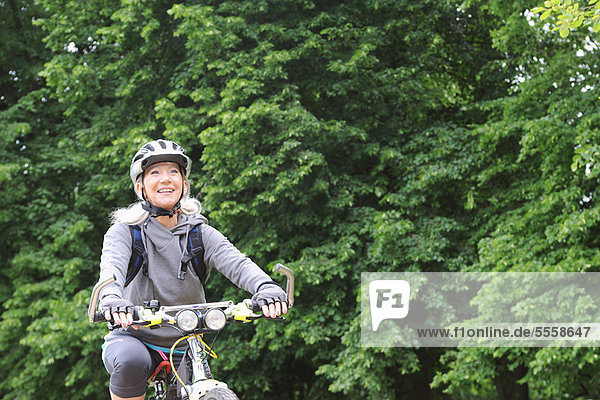 Older woman riding bicycle on rural road