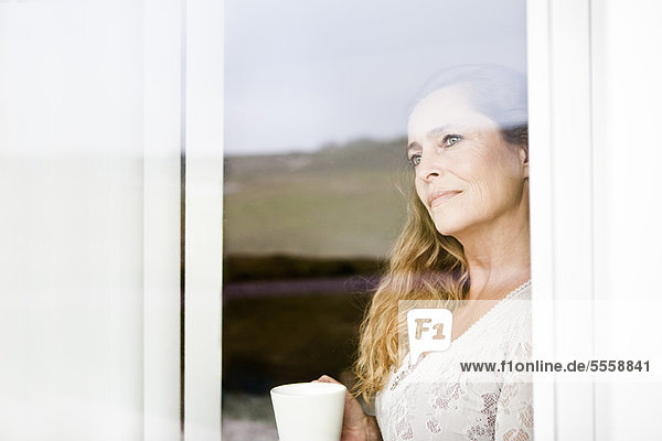 Frau bei einer Tasse Kaffee am Fenster