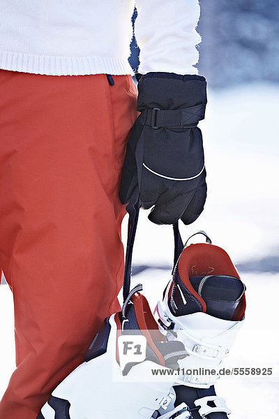 Person carrying ski boots in snow