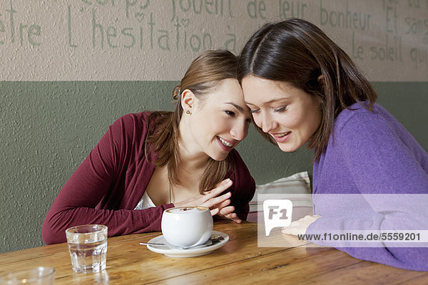 Frauen flüstern sich im Café zu.