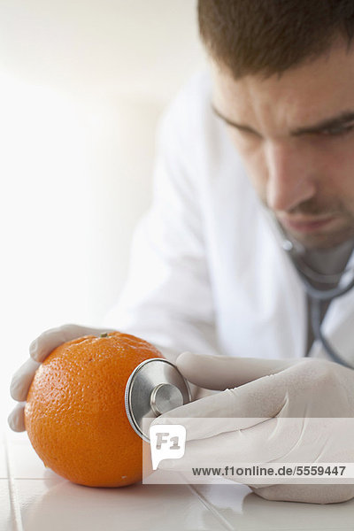 Wissenschaftler mit Stethoskop auf Orange