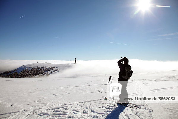 Cross-country skier enjoying the view from the summit of Feldberg Mountain towards Seebuck Mountain in the fog  Black Forest  Baden-Wuerttemberg  Germany  Europe  PublicGround