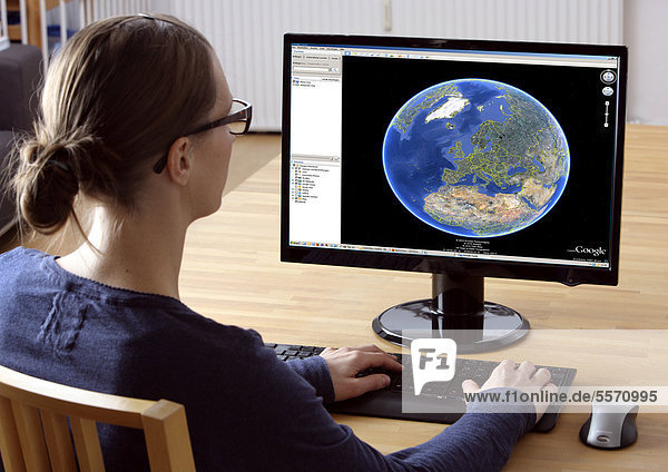 Frau am Computer surft im Internet  Google Earth