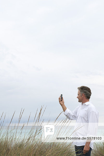 Erwachsener Mann fotografiert Szenerie mit Handy