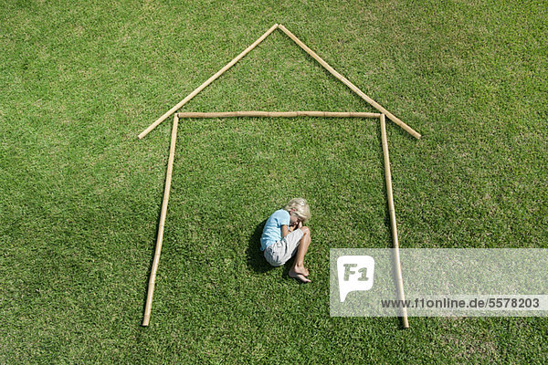 Boy in fetal position within outline of house  high angle view