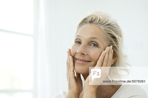 Mature woman touching cheeks  smiling  portrait