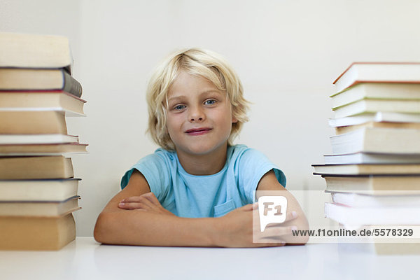 Boy sitting between two stacks of books  portrait