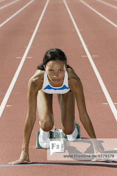 Woman crouched in starting position on running track