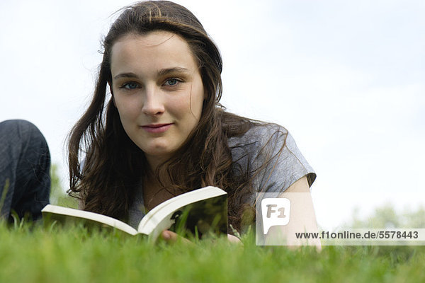 Junge Frau entspannt sich im Freien mit Buch  Porträt