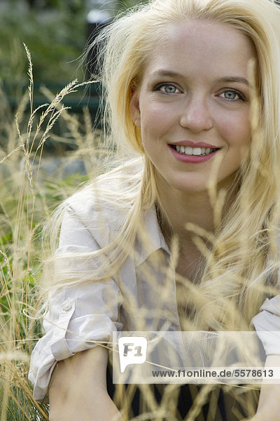 Young woman sitting in tall grass  portrait