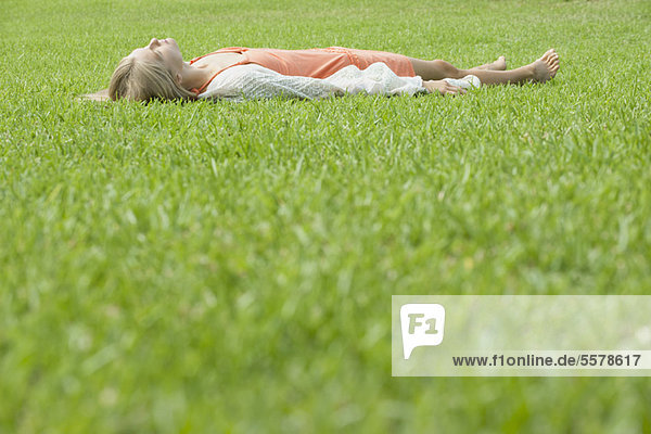Junge Frau schläft auf Gras