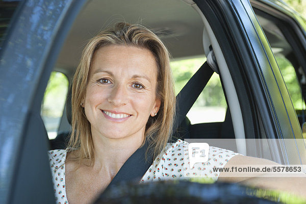 Frau im Auto  lächelnd aus dem Fenster  Portrait
