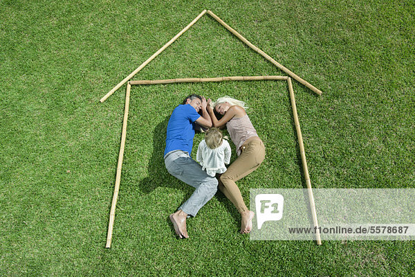 Little girl awake  parents sleeping  together within outline of house  high angle view