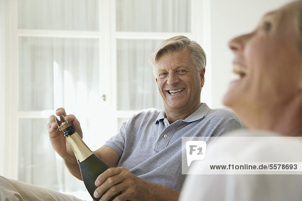 Paar entspannt zusammen  Mann öffnet Flasche Champagner