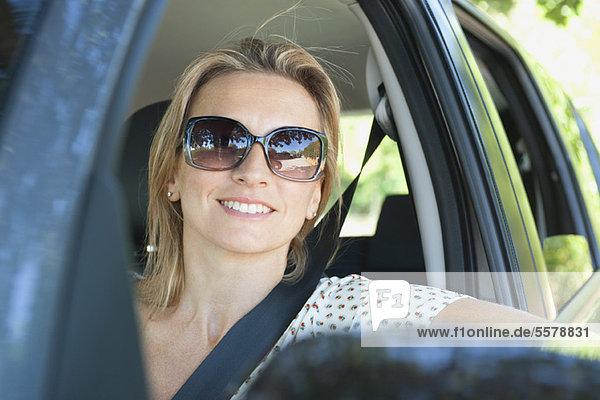 Frau im Auto  lächelnd aus dem Fenster  Portrait
