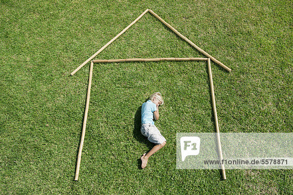 Junge auf Gras liegend in der Umrisslinie des Hauses,  hoher Blickwinkel