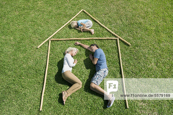 Family with one child lying on grass within outline of house  high angle view