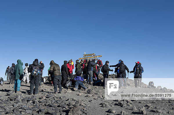Bergsteigen  Massentourismus  viele Bergsteiger am Schild auf dem Gipfel des Kilimandscharo  Mount Kilimanjaro  Kibo  Uhuru Peak  5895 m  Marangu-Route  Tansania  Ostafrika  Afrika