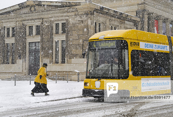 Frau eilt im Schnee zur Straßenbahn vor der Schinkelwache  Dresden  Sachsen  Deutschland  Europa  ÖffentlicherGrund