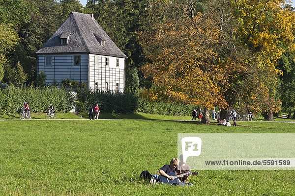 Young people playing guitar in front of Goethe's Garden House  Park an der Ilm  Weimar  Thuringia  Germany  Europe