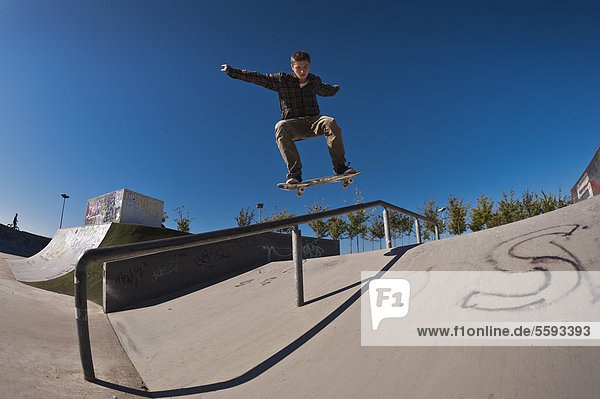 Germany  North Rhine-Westphalia  Duisburg  Skateboarder performing trick on ramp at skateboard park