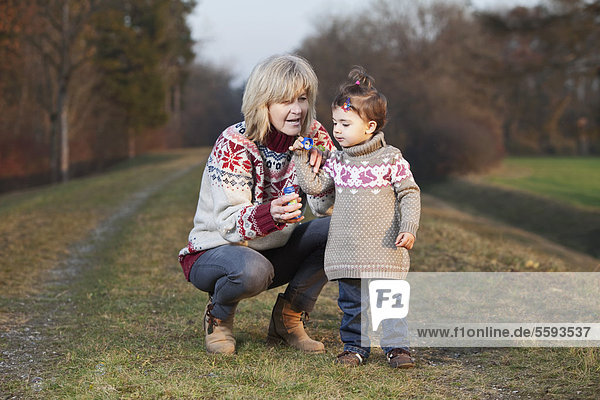 Germany  Upper Bavaria  Grandmother and granddaughter blowing bubbles